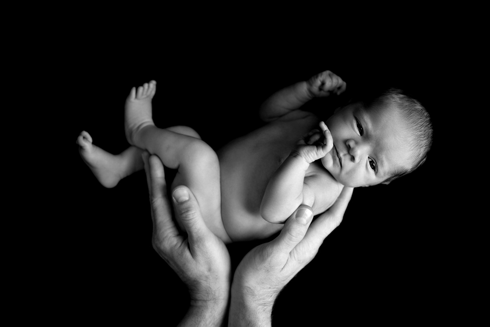 Photographie nouveau-né dans les mains du père noir et blanc